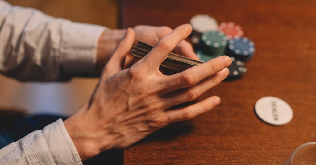 Hands holding cards and poker chips on a wooden table, capturing the gaming atmosphere.
